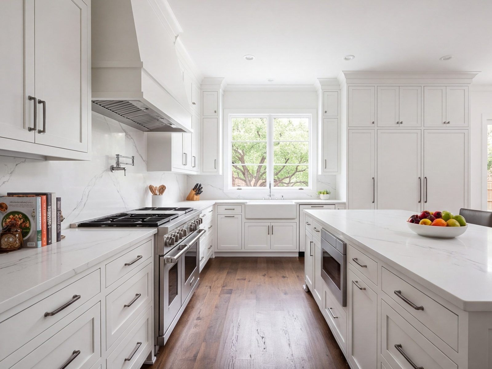 Open kitchen with a centered range and hood, stone counters and tall pantry cabinets